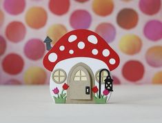 a small house with a red mushroom on the roof and flowers in front of it