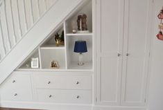 a white bookcase with drawers underneath a stair case