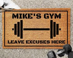 a door mat that says mike's gym and two dumbbells on it