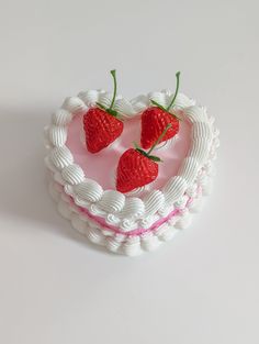 three strawberries on top of a heart shaped cake