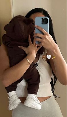 a woman is taking a selfie with her cell phone while holding a baby in her arms