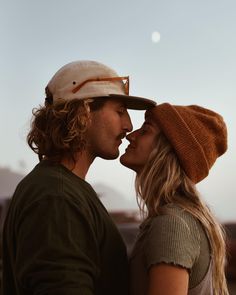 a man and woman standing next to each other in front of the moon with their heads together