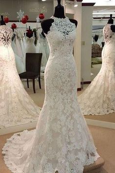 a white wedding dress on display in front of a mirror with other dresses behind it