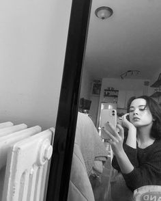 a woman looking at her cell phone while sitting in front of a radiator