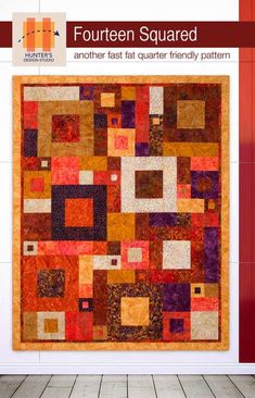 an orange and red quilt hanging on the wall