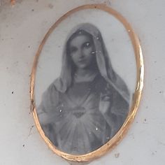 an old photo of a woman with long hair in a gold frame on the wall