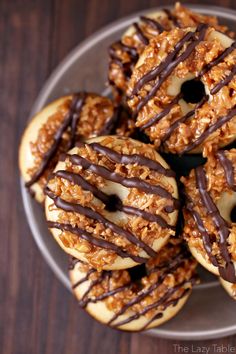 a plate full of donuts with chocolate drizzled on top and nuts in the middle