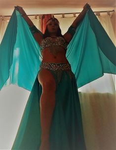 a woman in a belly dance outfit with her hands on her hips and arms behind her head