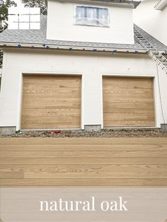 a white house with wood garage doors and the words natural oak painted on it