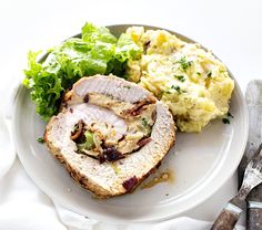 a white plate topped with meat and mashed potatoes next to a knife and fork