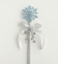 a blue and white snowflaked flower on a stick with ribbon tied around it