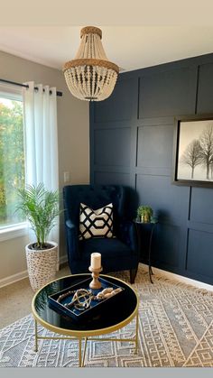 a living room with a blue couch, coffee table and chandelier hanging from the ceiling