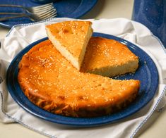 a blue plate topped with a piece of cake next to a fork and knife on top of a table