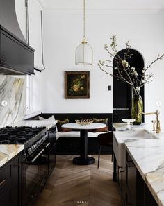 a kitchen with marble counter tops and black cabinets, along with an oval dining table