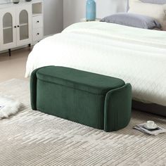 a bedroom with a large bed and green storage box on the floor next to it