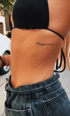 the back of a woman's stomach with her name tattooed on it, in front of a motorcycle