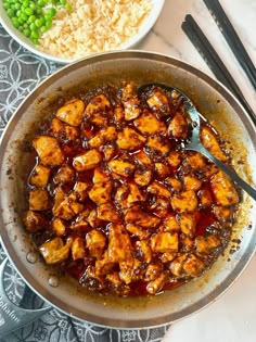 a pan filled with food next to rice and peas