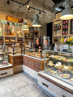 two people behind the counter of a bakery