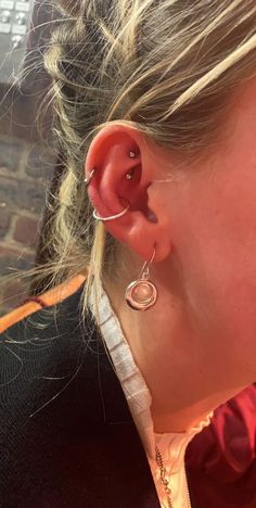 a close up of a person wearing ear piercings and an earring on their left side