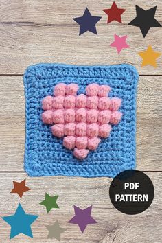 a crocheted square with pink hearts in the center and stars around it on a wooden background