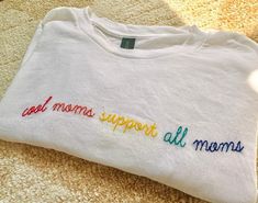 Introducing our beautifully hand-embroidered "Mom Squad" T-shirt, designed to celebrate the strength, resilience, and unity of mothers everywhere. Crafted from soft, premium 100% cotton, this shirt features a delicate yet bold hand-stitched design that symbolizes the power of moms lifting each other up.  **Cool Moms support All Moms will be in rainbow colors unless otherwise stated in Personalization tab. If you would like to change to different colors, please state which color theme you would like to replace it with* Mom Support, Beste Mama, Color Theme, Embroidered Tshirt, Color Themes, Best Mom, Hand Stitched, Rainbow Colors, Womens Clothing Tops