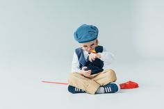 a little boy sitting on the floor with a pencil in his mouth and wearing a blue hat