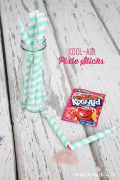 two striped paper straws and a kool - aid drink on a white wooden table