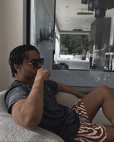 a man sitting on top of a couch holding a cell phone to his ear while wearing sunglasses