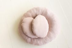 two pink pillows sitting on top of a white floor next to each other in the shape of an egg