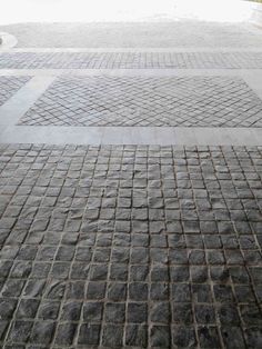 a person with an umbrella is walking down the street in front of some brick pavement