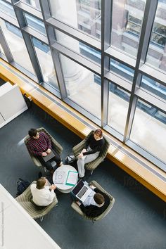 three people sitting at a table in front of large windows by luma studio for stocks on artfire