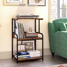 a living room with a green couch and two pictures on the wall above a bookshelf