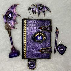 a purple book with an evil eye and some other items around it on a white surface