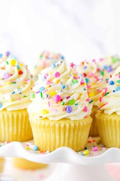 cupcakes with white frosting and sprinkles on a plate