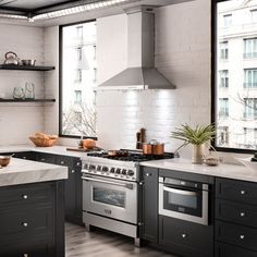 a kitchen with black cabinets and white counter tops, an island in the middle is surrounded by pots and pans