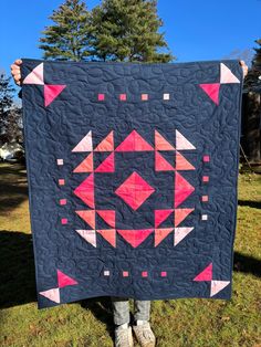 a person holding up a quilt in the grass