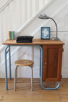 a wooden desk with a computer on it and a chair next to it in front of a stair case