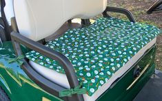 the back end of a golf cart with a green and white seat cover on it