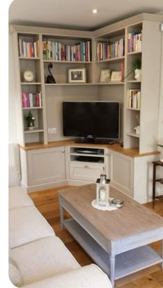 a living room filled with furniture and a flat screen tv on top of a wooden table