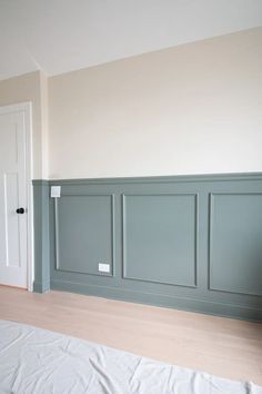 an empty room with wood flooring and walls painted in pale blue, white and beige