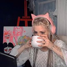 a girl with cat ears drinking from a mug