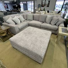 a couch and ottoman in a store with lots of furniture on the shelves behind it