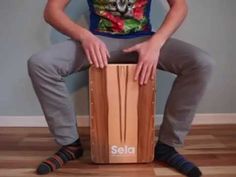 a man sitting on top of a wooden box with his hands on the back of it