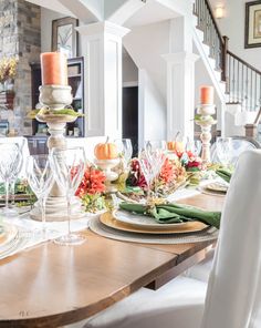 a dining room table set with plates and candles