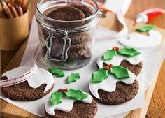 cookies decorated with green and white icing are on a cutting board next to a jar