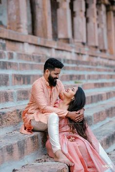 a man and woman sitting on steps with their arms around each other, smiling at each other