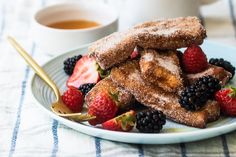 french toast with berries and strawberries on a plate next to a cup of coffee