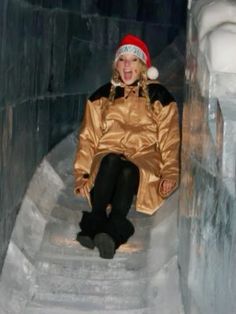 a woman sitting on top of a set of stairs wearing a santa hat and gold coat