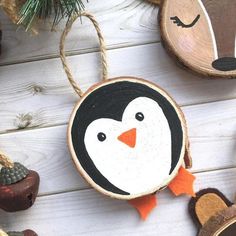 a penguin ornament hanging from a string next to other ornaments on a white wooden surface