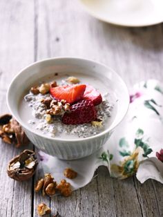 a bowl of oatmeal with strawberries and walnuts on the side